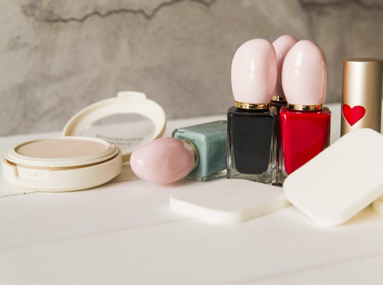 maquillaje-cosmetico-facial-de-polvo-compacto-con-esponjas-esmalte-de-unas-botella-y-lapiz-labial-en-la-mesa